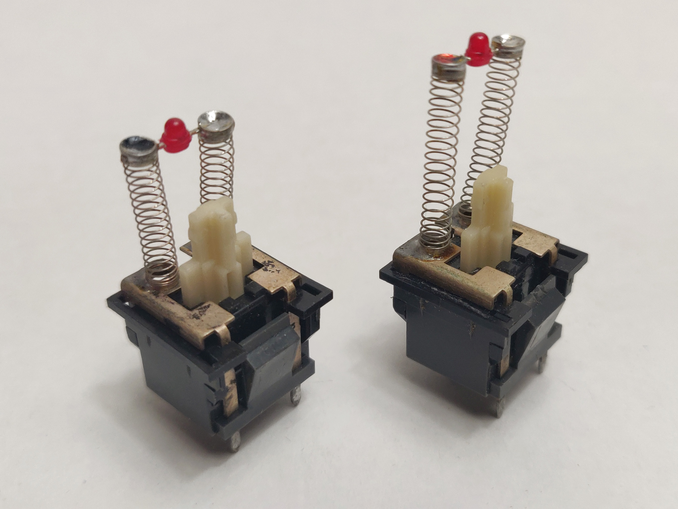 Two desoldered Alps SKCC Cream LED switches with different LED spring lengths